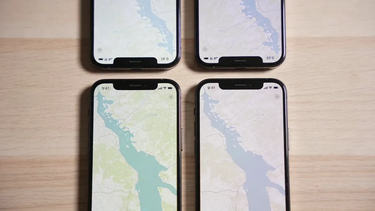 Top-down flat lay of four modern smartphones arranged in a clean grid on a wooden surface